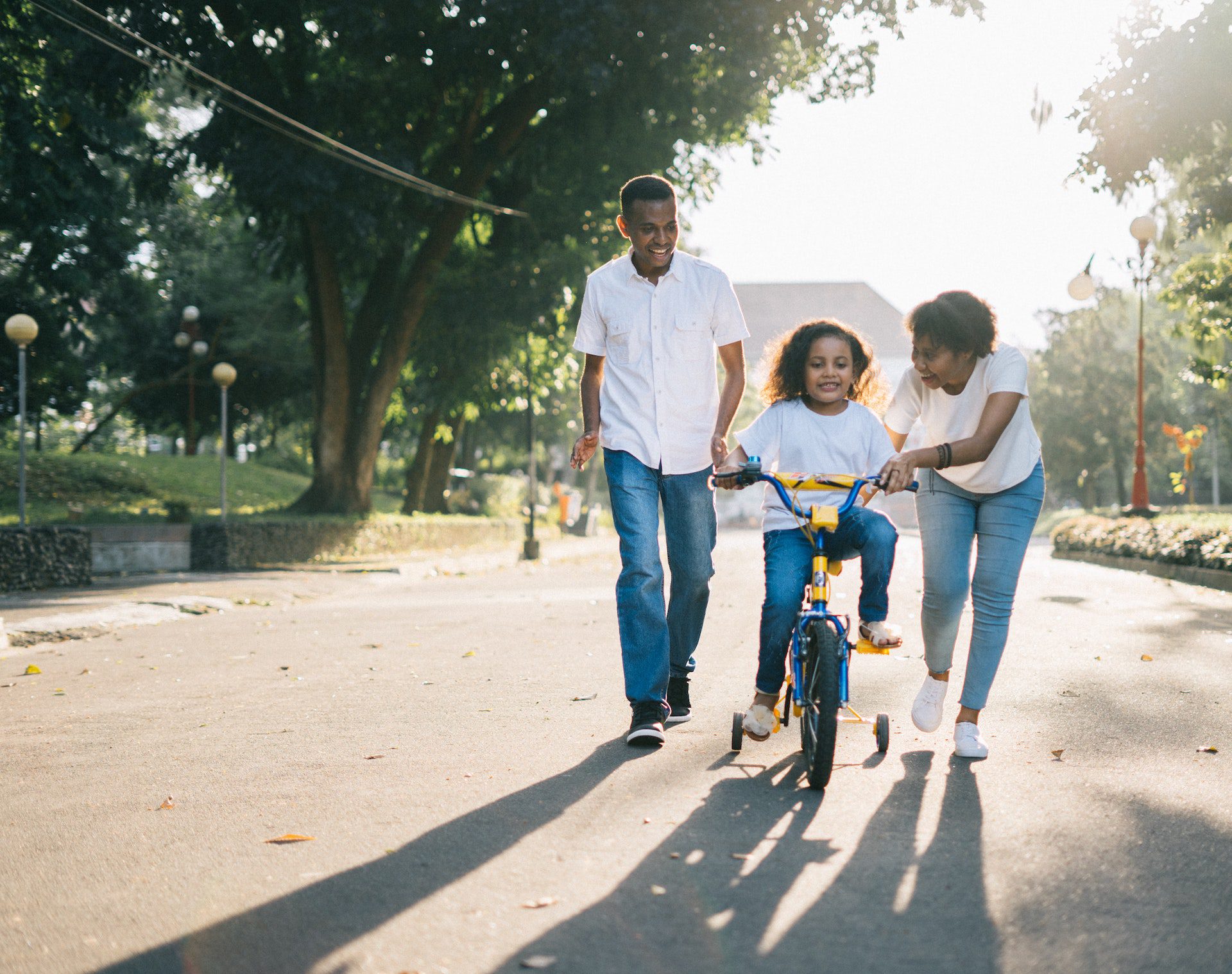 Family teaching child to ride a bicycle