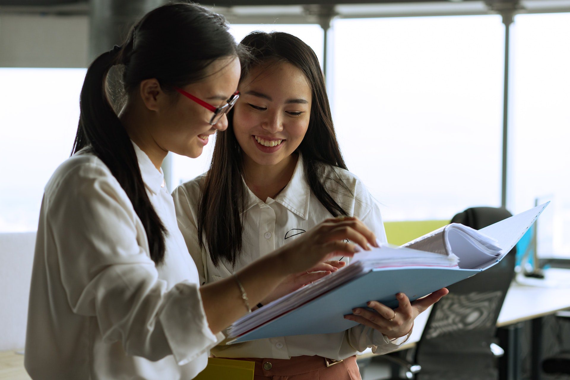 Two women looking at book binder papers