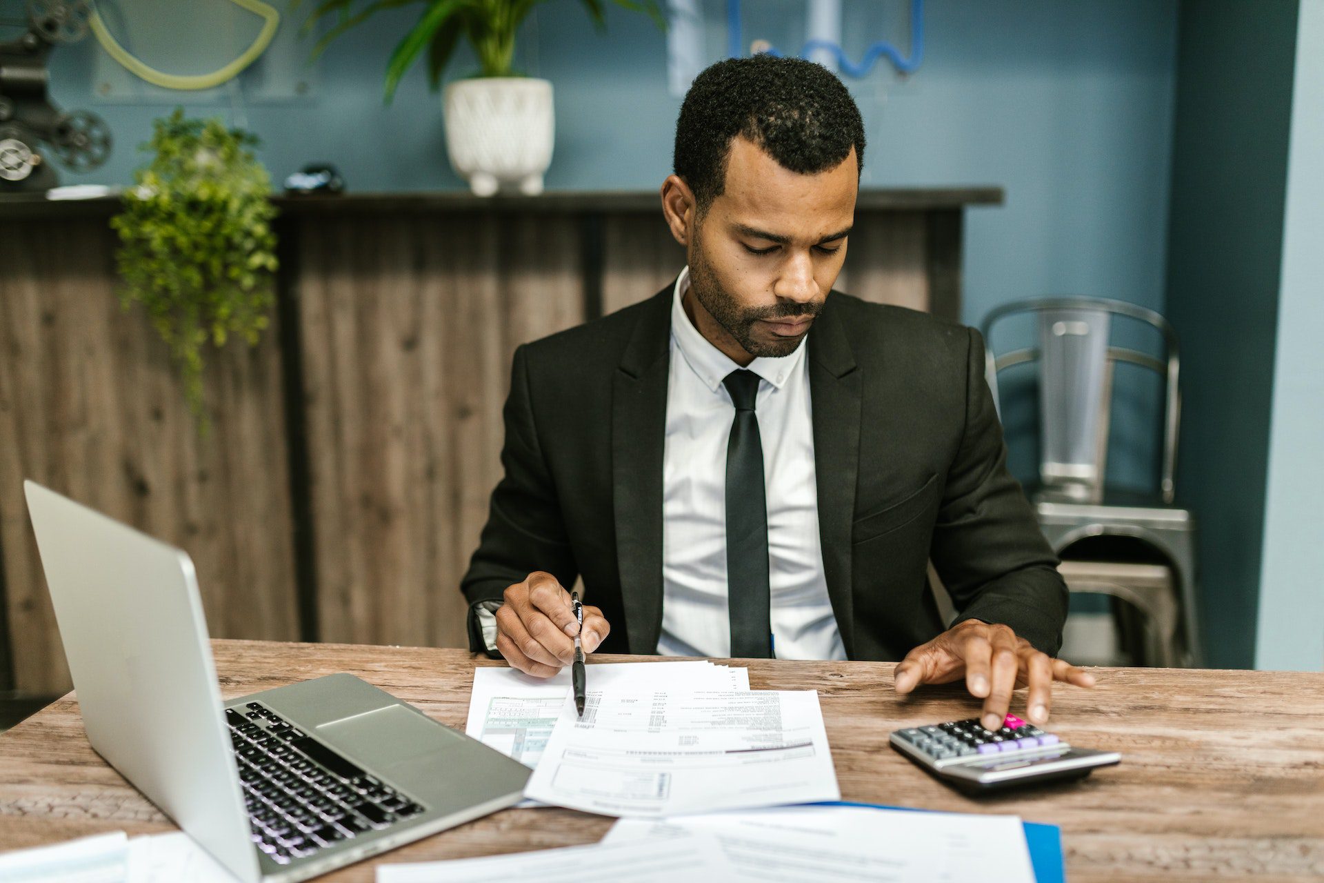 Man with calculator, laptop, and papers